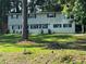 Two-story home with light siding, black shutters and a green lawn surrounded by tall trees at 2510 Lakeshore Ne Dr, Conyers, GA 30012