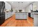 Open kitchen boasts an island, wooden floors, stainless steel appliances, and pendant lights at 828 Ivy Ne Cv, Norcross, GA 30071