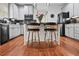 Open kitchen features a black appliance suite, central island, wooden floors and light cabinets at 828 Ivy Ne Cv, Norcross, GA 30071