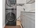 Modern laundry room featuring a stacked washer and dryer, gray cabinets, and light wood flooring at 828 Ivy Ne Cv, Norcross, GA 30071
