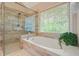 Modern bathroom features a separate glass shower and a soaking tub beneath a bright window at 3130 Crestmont Nw Way, Kennesaw, GA 30152