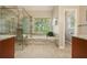 Bright bathroom features a glass shower, soaking tub under a window, and neutral tile floors at 3130 Crestmont Nw Way, Kennesaw, GA 30152
