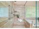A glass enclosed shower features neutral tile, with a window and soaking tub nearby at 3130 Crestmont Nw Way, Kennesaw, GA 30152