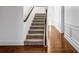 The carpeted stairway features a wood railing and trim and leads to a hardwood landing at 7601 Watson Cir, Locust Grove, GA 30248