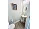 Cozy half bathroom with a pedestal sink, oval mirror, and modern wood-look flooring at , Covington, GA 30014