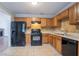 This kitchen includes tiled floors, wooden cabinets, and black appliances at 1214 Tyne Way, Stone Mountain, GA 30088