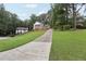 Wide shot of the front yard showcasing the long driveway, trees and front of the property at 5276 Beechwood Ct, Marietta, GA 30068