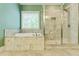 Well-lit bathroom featuring a soaking tub and glass enclosed shower with marbled tile surround at 3821 Chamblee Dunwoody Rd, Atlanta, GA 30341