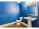 Stylish powder room features a pedestal sink, blue walls, and wood floors at 3821 Chamblee Dunwoody Rd, Atlanta, GA 30341