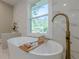 Bright bathroom featuring a soaking tub with gold fixtures near a window with a view of nature at 4446 Huntington Cir, Atlanta, GA 30338