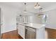 Open-concept kitchen with white island, stainless steel dishwasher, and hardwood floors, connecting seamlessly to other rooms at 1824 Westwood Sw Ave, Atlanta, GA 30310