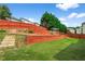 Backyard featuring a red fence, tiered garden beds with retaining walls, and lush green lawn at 3652 Terrah Point Dr, Duluth, GA 30097