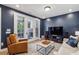 Cozy living room features a comfortable seating area, dark blue accent wall, and view to the covered patio at 408 Townly Ct, Alpharetta, GA 30009