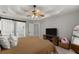 A cozy bedroom features tray ceilings, a ceiling fan and a modern entertainment center at 5510 Pilgrim Point Ext, Cumming, GA 30041