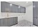 Laundry room with gray cabinets, quartz countertop, stainless sink, and marble-look tile floor at 115 Nova Lane, Roswell, GA 30075