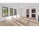 Bright living room with hardwood floors, three windows with black trim and an entry to a bathroom at 115 Nova Lane, Roswell, GA 30075