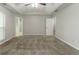Bedroom featuring neutral paint and carpet and tray ceiling with ceiling fan, with an open bathroom doorway at 2191 Phillips Rd, Lithonia, GA 30058
