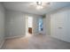 A carpeted bedroom featuring a ceiling fan, closet, and view into bathroom and stairs at 2482 Brittany Park Ln, Ellenwood, GA 30294
