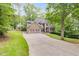 Beautiful home with mature trees, manicured lawn, long driveway, and a mix of stone and siding on the exterior at 1058 Magnolia Dr, Villa Rica, GA 30180