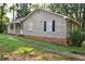 Side exterior of a single-story home, featuring wood siding, dark shutters, and a brick foundation and mature landscaping at 157 Sequoyah Cir, Canton, GA 30115