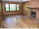 Cozy living room featuring a brick fireplace, wood-paneled walls, and large windows overlooking a green yard at 157 Sequoyah Cir, Canton, GA 30115