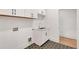 Well-lit laundry room featuring white cabinets, a sink, black hexagonal tile flooring, and modern fixtures at 504 Barrington Drive, Roswell, GA 30075