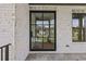 Close up of the home's modern, black-framed front entry door and stone porch with black railings at 6132 Hutchins Dr, Buford, GA 30518