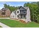 Beautiful two-story home with painted brick, black trim, and a green front lawn in wooded setting at 6132 Hutchins Dr, Buford, GA 30518
