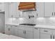A modern kitchen features white cabinets, quartz countertops, herringbone backsplash, and a professional gas range at 6132 Hutchins Dr, Buford, GA 30518