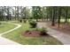 Well-maintained yard features a winding walkway, lush green grass, and mature trees creating a park-like setting at 10 Stagg Trce, Social Circle, GA 30025