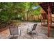 A serene stone backyard patio with chairs is surrounded by lush trees, brick and a two-story building at 1038 Saint Charles Ave, Atlanta, GA 30306