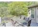 View of a deck with a grill, dining table, chairs and surrounding lush green trees at 1641 Rocky Knoll Ln, Dacula, GA 30019