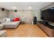 Cozy basement area with a stone wall, hardwood floors, speakers, and large comfortable sectional at 1164 Bonview Ne Ln, Atlanta, GA 30324