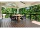 Covered outdoor patio features a dining set with wooden floors, seating, and wooded backyard views at 1164 Bonview Ne Ln, Atlanta, GA 30324