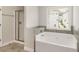 Bathroom featuring tile floor, tiled backsplash, soaking tub, and glass enclosed shower at 829 Overlook Path Ln, Lawrenceville, GA 30045