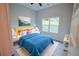 Bedroom featuring a blue bedspread, neutral walls, and a large window with verdant outdoor views at 275 Green Commons Dr, Covington, GA 30016