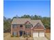 Charming two-story brick home featuring blue shutters, a well-manicured lawn and an attached two-car garage at 403 Sonja Ln, Loganville, GA 30052