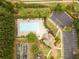 Aerial view of the community swimming pool, parking lot, common green spaces, and nearby homes surrounded by trees at 2059 Ivey Chase Dr, Dacula, GA 30019