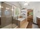 This tiled bathroom showcases a glass shower, soaking tub with shelves, and natural light at 2059 Ivey Chase Dr, Dacula, GA 30019