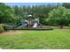 Community playground with slides, climbing structure, and benches surrounded by green grass and mature trees at 2059 Ivey Chase Dr, Dacula, GA 30019