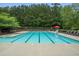 Community pool with clear blue water, lane dividers, and several lounge chairs, shaded umbrellas, and greenery at 2059 Ivey Chase Dr, Dacula, GA 30019