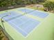 Community tennis courts with blue surface, green surround, nets, lighting and fenced perimeter near mature trees at 2059 Ivey Chase Dr, Dacula, GA 30019