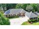 Beautiful brick home featuring a gray roof, attached garage, mature trees, and large driveway at 1758 N Springs Dr, Atlanta, GA 30338
