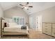 Bedroom with vaulted ceiling, ceiling fan, neutral decor, and shuttered window at 2377 Kesgrove Way, Buford, GA 30518