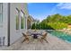 Outdoor patio with stone pavers, wood furniture, and a view of the pool and greenery at 2377 Kesgrove Way, Buford, GA 30518