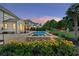Beautifully landscaped backyard pool area with yellow flowers and a stone waterfall feature, ideal for outdoor enjoyment at 2377 Kesgrove Way, Buford, GA 30518
