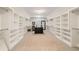 Spacious walk-in closet with custom shelving, carpeted floor and center island for storing clothes and accessories at 2377 Kesgrove Way, Buford, GA 30518