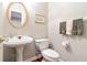 Elegant powder room with pedestal sink, decorative mirror, and neutral color palette at 5365 Twin Creeks Dr, Norcross, GA 30071