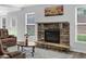 Cozy living room with stone fireplace, plush seating, and natural light from multiple windows at 6135 Stillwood Ln, Cumming, GA 30041