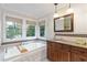 Bathroom with tub, wooden cabinets, granite countertops, and modern fixtures at 1268 Harris Road Rd, Lawrenceville, GA 30043